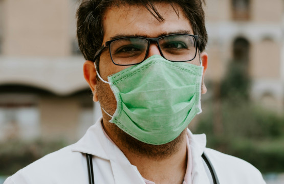 man in white scrubs wearing green mask